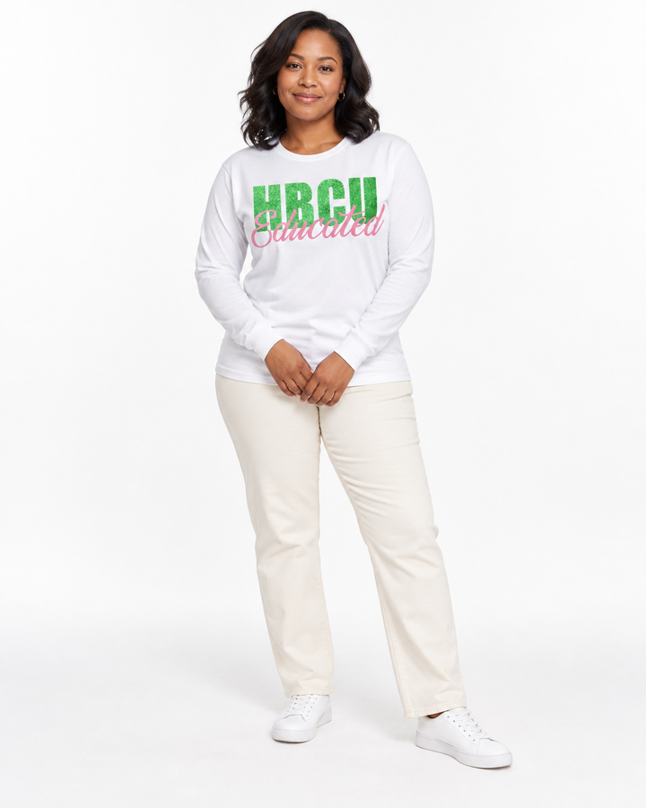 Model with hands loosely clasped wearing a white long-sleeve HBCU Educated Tee with green glitter lettering and matte pink script.
