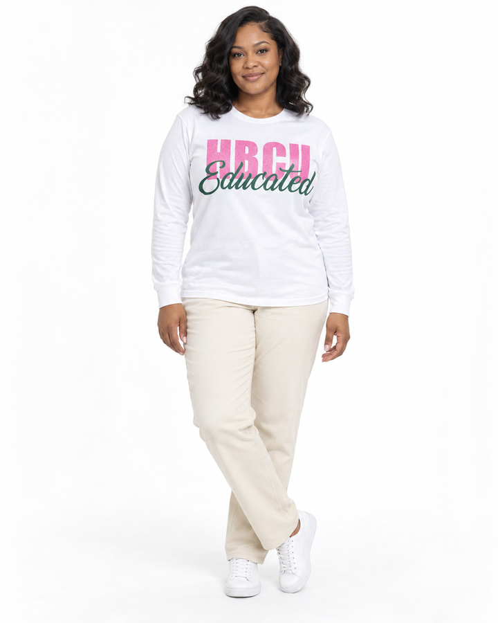 Model in a relaxed crossed-ankle pose wearing a white long-sleeve HBCU Educated Tee with pink glitter lettering and matte green script.