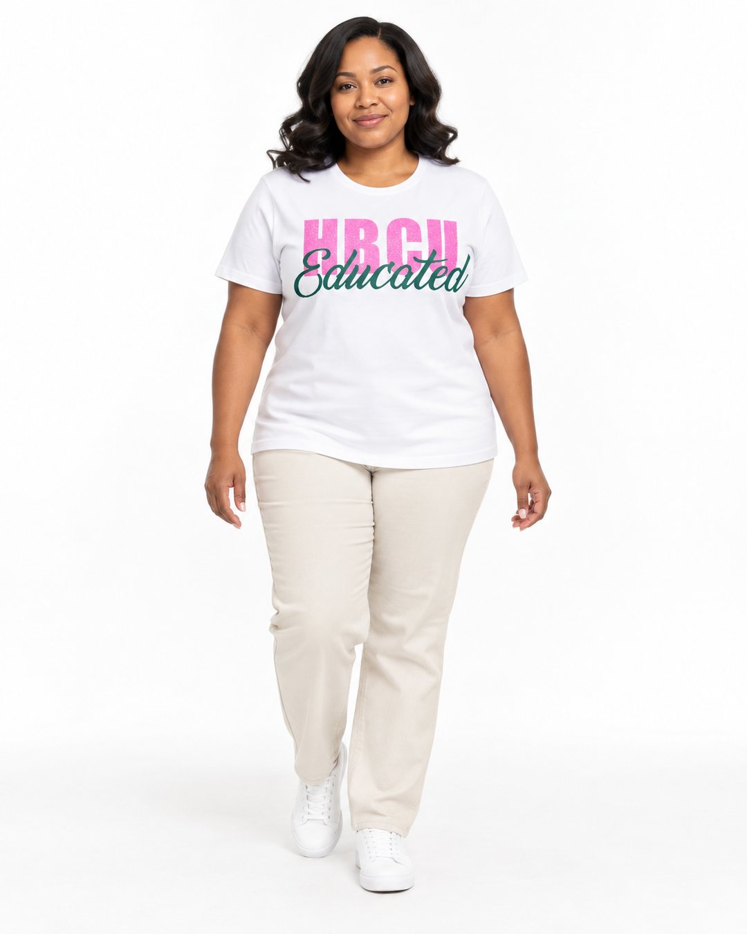 Model in a relaxed walking pose wearing a white short-sleeve HBCU Educated Tee with pink glitter lettering and matte green script.